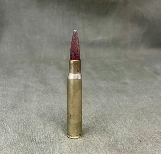 Metallic bullet casing with a red tip on a gray background