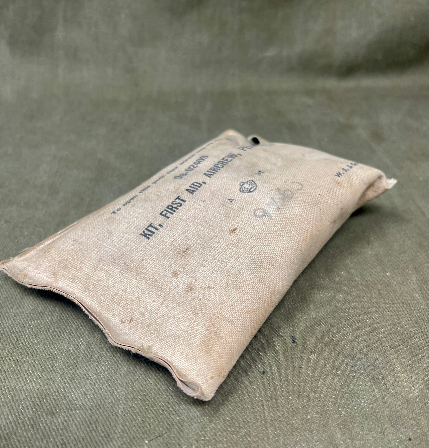 Vintage first aid kit pouch on a textured green background