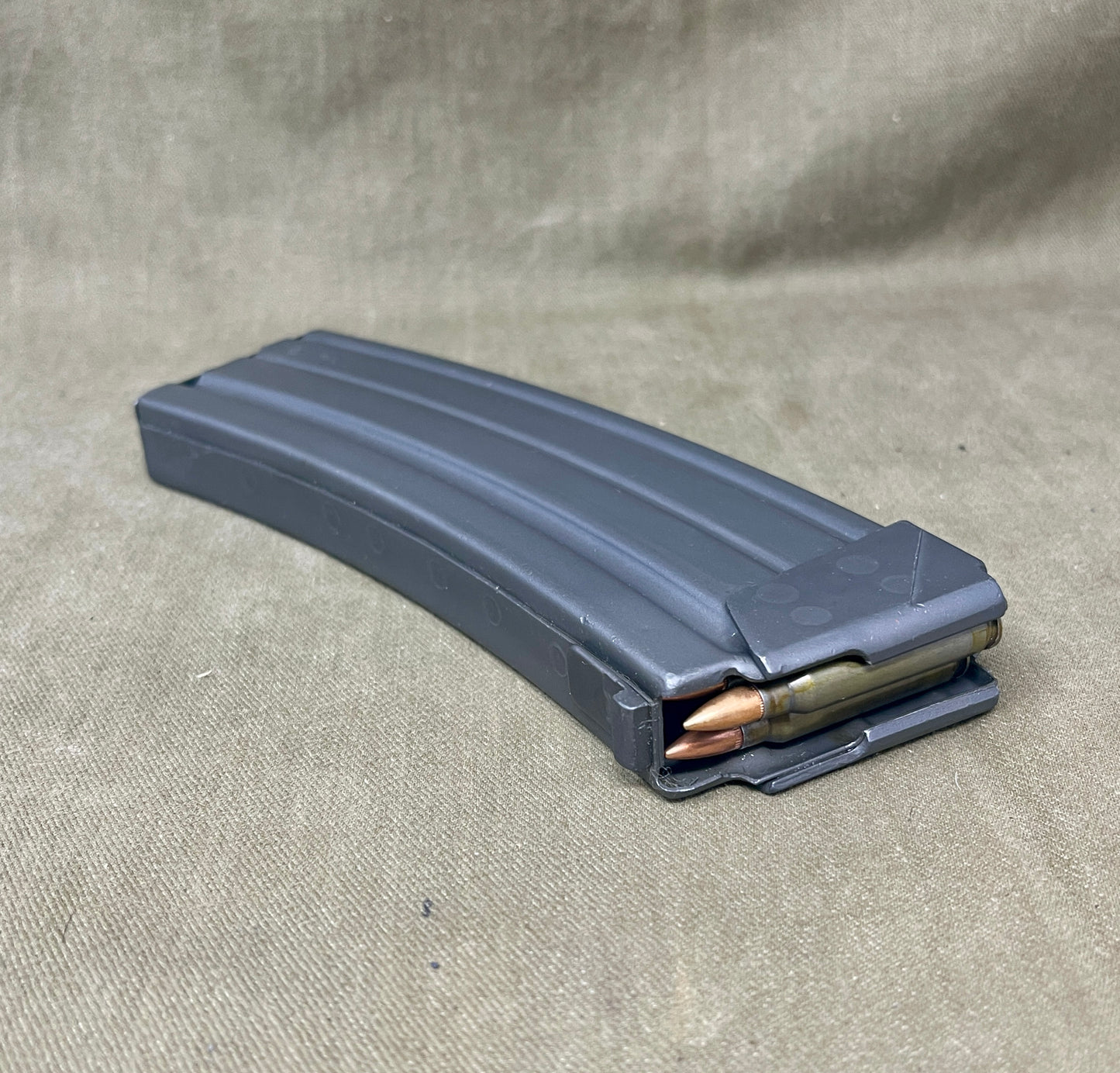 Gray rifle magazine with ammunition on a beige fabric background