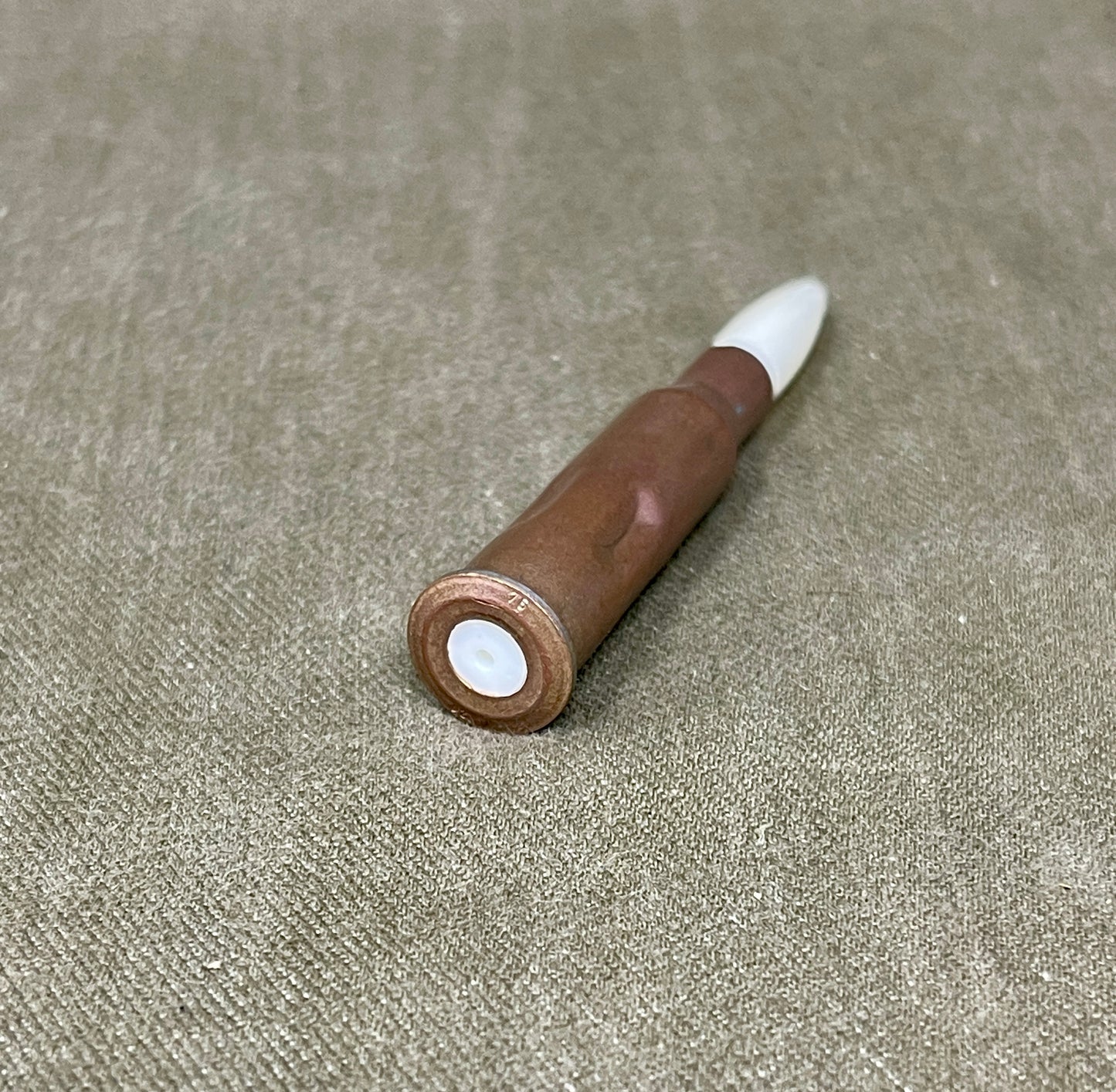 Wooden pen with white cap on a beige fabric background