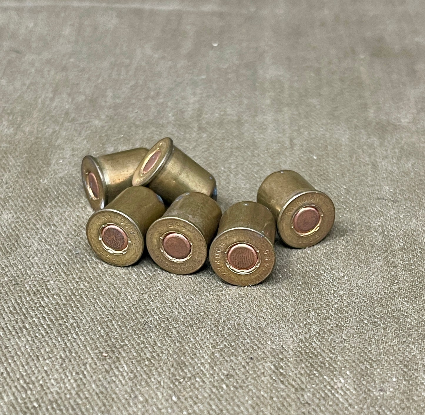 Set of six brass-colored ammunition casings on a gray fabric background