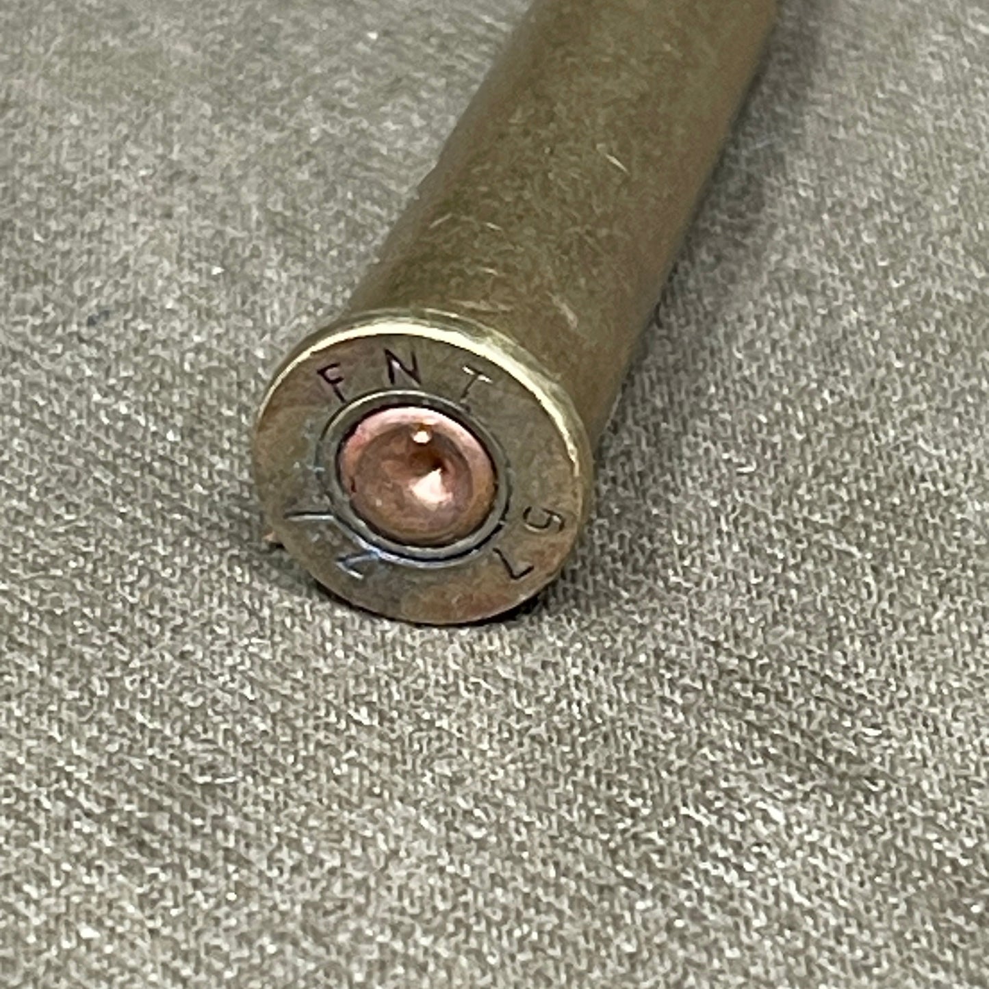 Close-up of a bullet casing on a textured gray surface