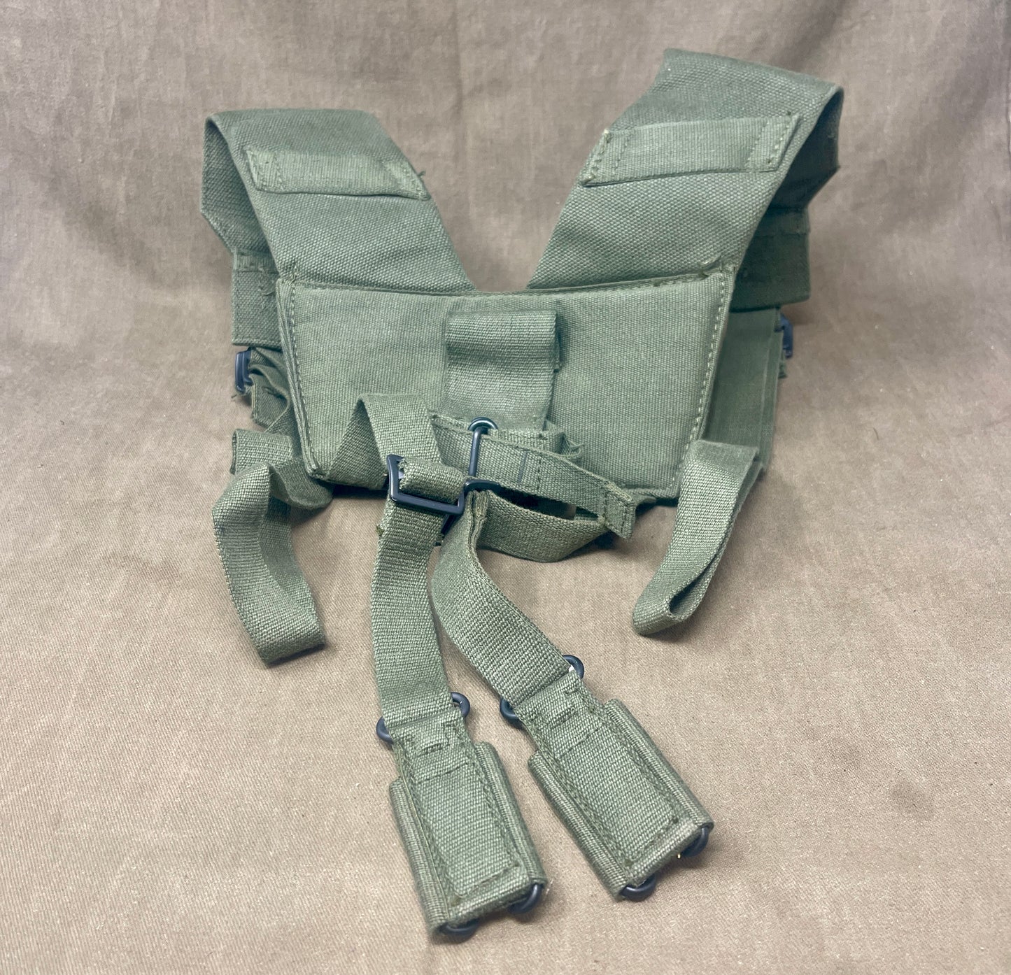 This is an original British Army 1958 Pattern Webbing Yoke, a vital component of the iconic '58 Pattern personal load-carrying system. Issued throughout the Cold War period, this yoke was designed to evenly distribute the weight of webbing pouches and equipment across the shoulders for improved comfort during extended operations.
Constructed from durable olive green webbing, the yoke features adjustable straps, metal fittings, and reinforced stitching for reliable use in the field. It connects securely to