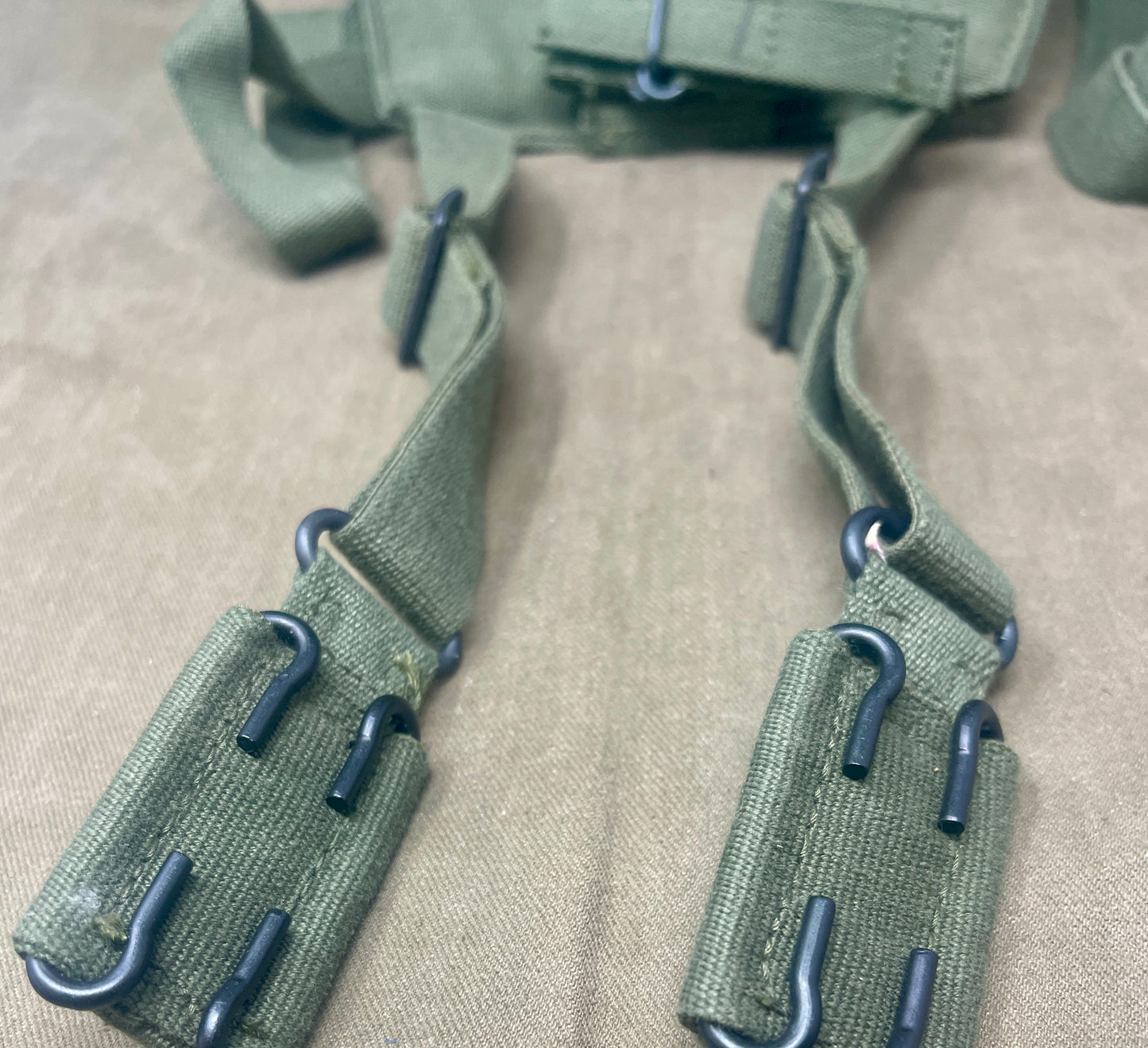 This is an original British Army 1958 Pattern Webbing Yoke, a vital component of the iconic '58 Pattern personal load-carrying system. Issued throughout the Cold War period, this yoke was designed to evenly distribute the weight of webbing pouches and equipment across the shoulders for improved comfort during extended operations.
Constructed from durable olive green webbing, the yoke features adjustable straps, metal fittings, and reinforced stitching for reliable use in the field. It connects securely to