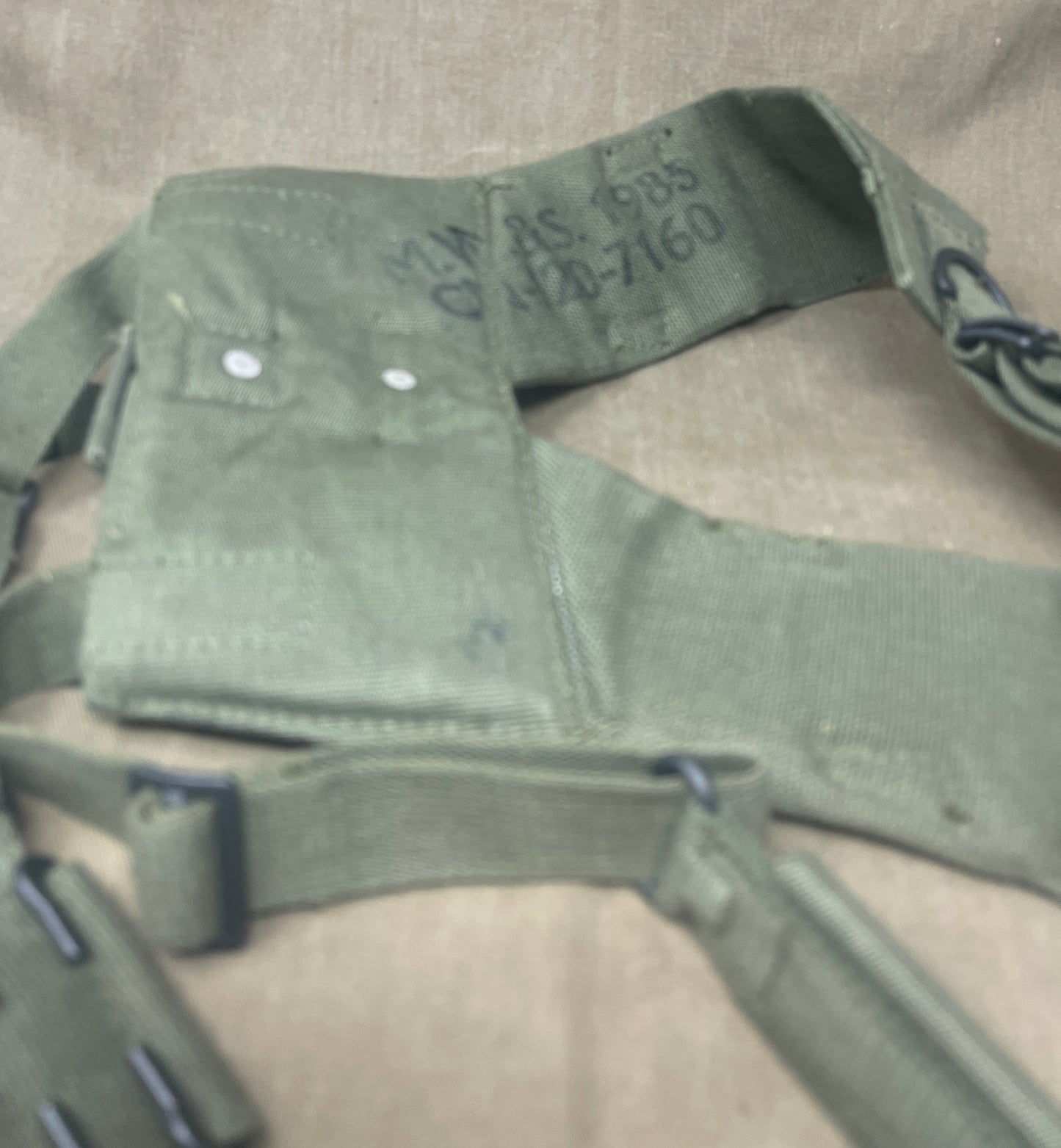 This is an original British Army 1958 Pattern Webbing Yoke, a vital component of the iconic '58 Pattern personal load-carrying system. Issued throughout the Cold War period, this yoke was designed to evenly distribute the weight of webbing pouches and equipment across the shoulders for improved comfort during extended operations.
Constructed from durable olive green webbing, the yoke features adjustable straps, metal fittings, and reinforced stitching for reliable use in the field. It connects securely to