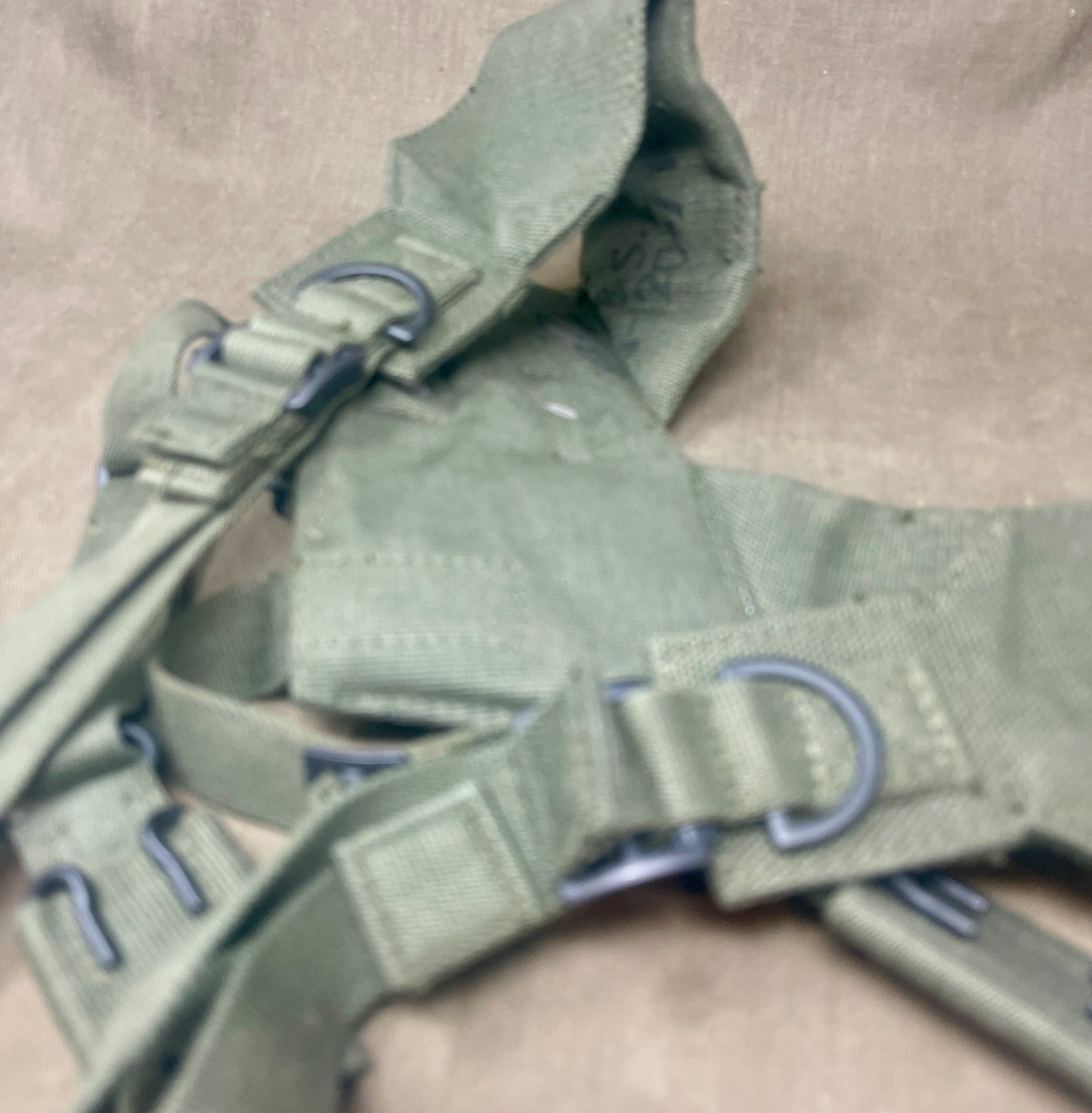 This is an original British Army 1958 Pattern Webbing Yoke, a vital component of the iconic '58 Pattern personal load-carrying system. Issued throughout the Cold War period, this yoke was designed to evenly distribute the weight of webbing pouches and equipment across the shoulders for improved comfort during extended operations.
Constructed from durable olive green webbing, the yoke features adjustable straps, metal fittings, and reinforced stitching for reliable use in the field. It connects securely to