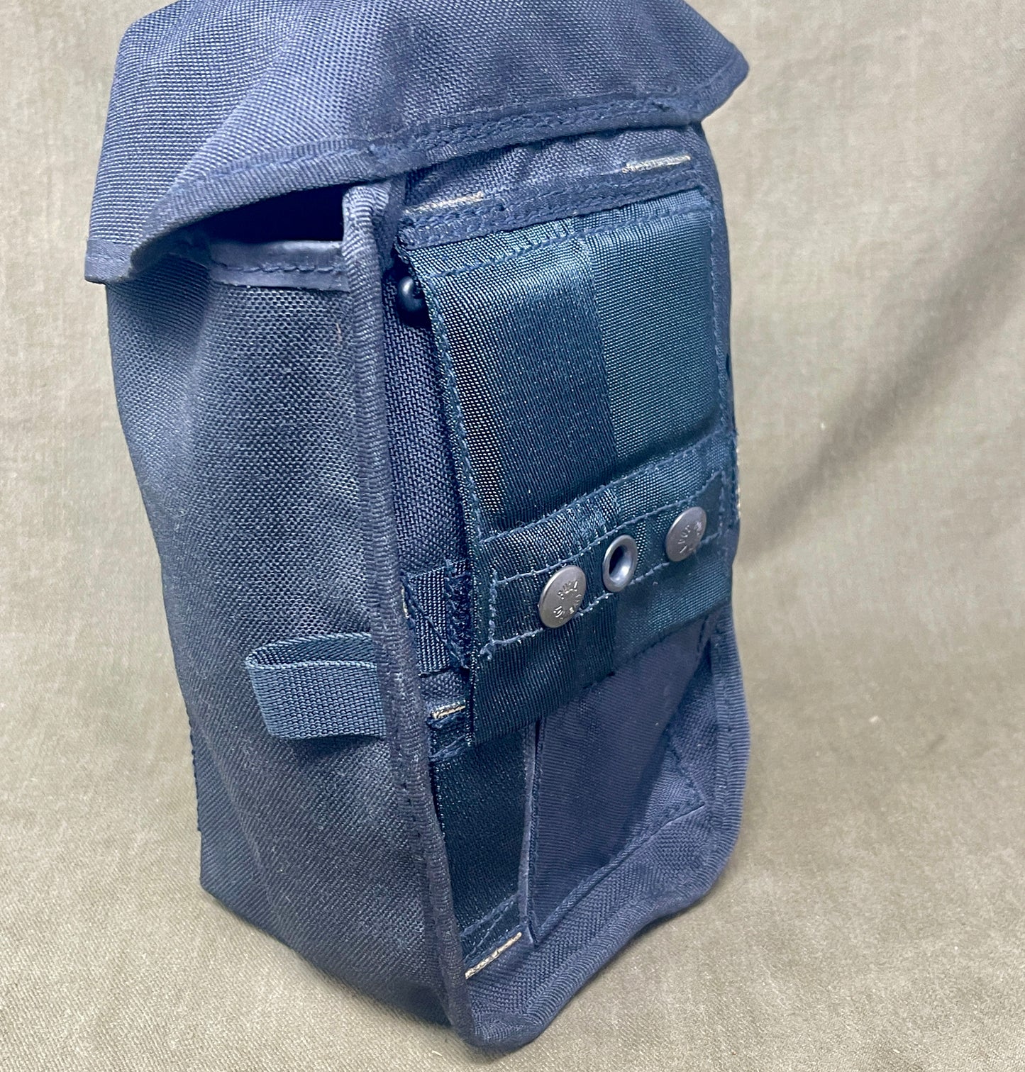 Blue bag with multiple pockets and buttons on a beige background