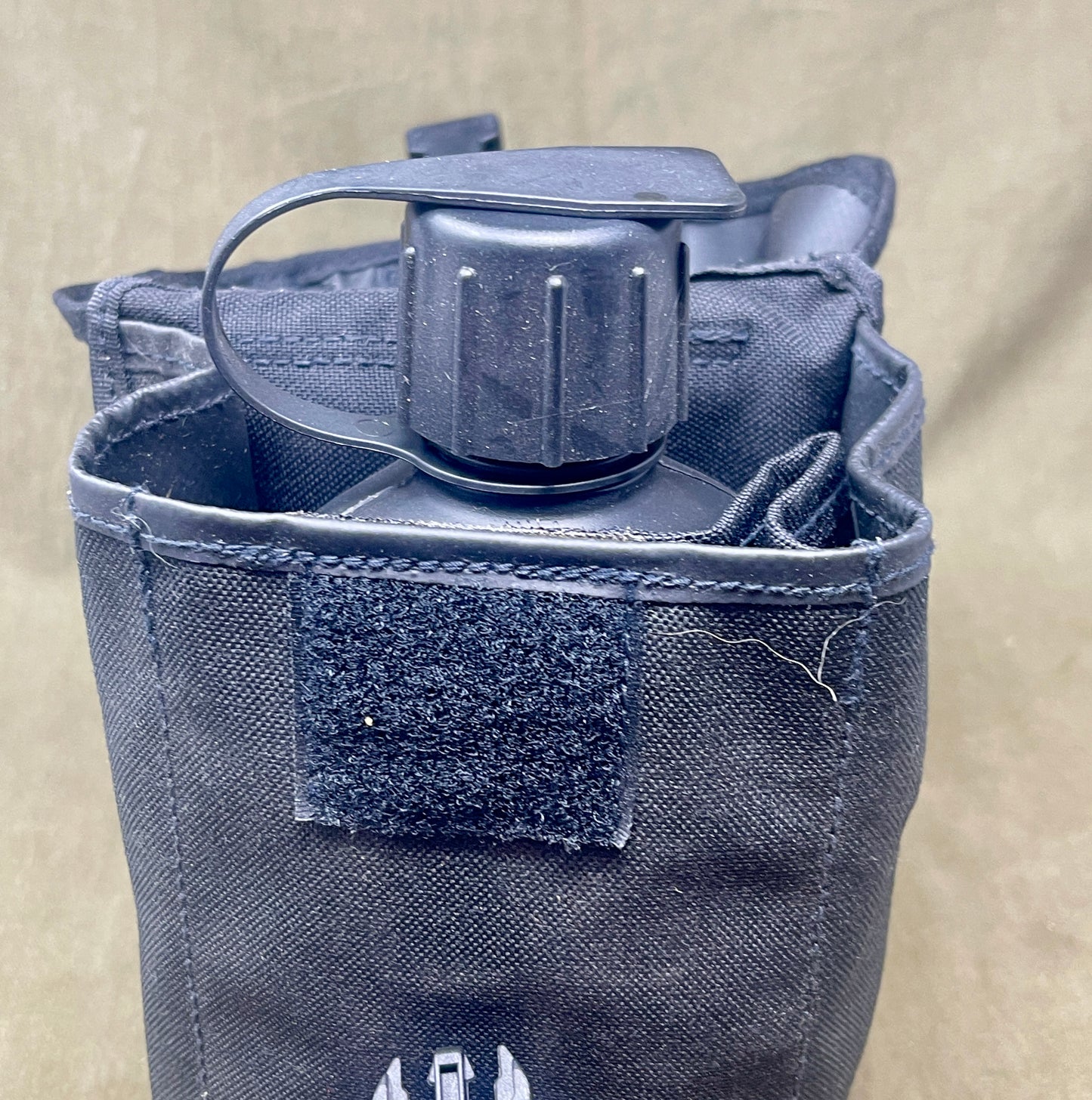 Gray water bottle holder with a water bottle on a beige background