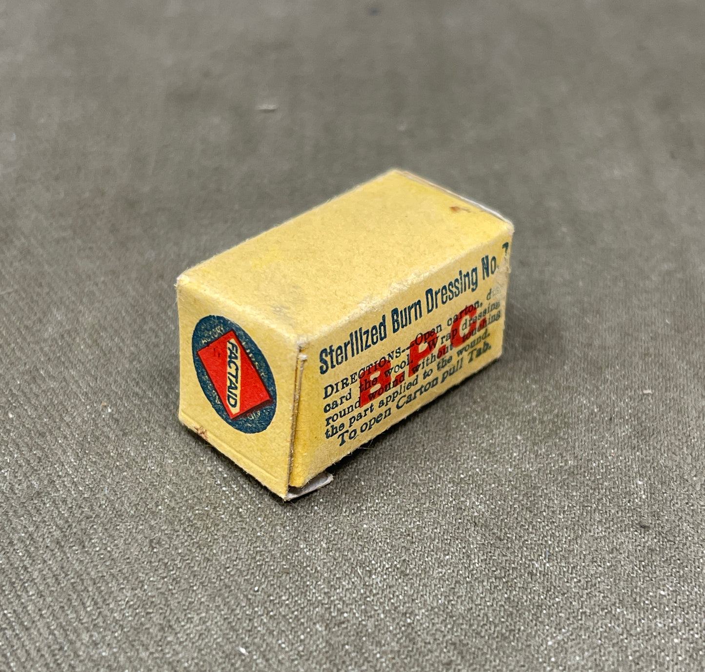 This authentic WWII Johnson’s W.O.W (White Open Wove) Bandage, measuring 1 inch by 4 yards, was a standard component of British military medical kits. Manufactured to B.P.C. (British Pharmacopoeia Cotton) standards, it was designed for securing dressings and treating wounds in the field. Produced by Johnson & Johnson, a key supplier to Allied forces, this bandage reflects the durable and practical nature of WWII medical supplies. Retaining its original wartime packaging and markings, it is a valuable item f