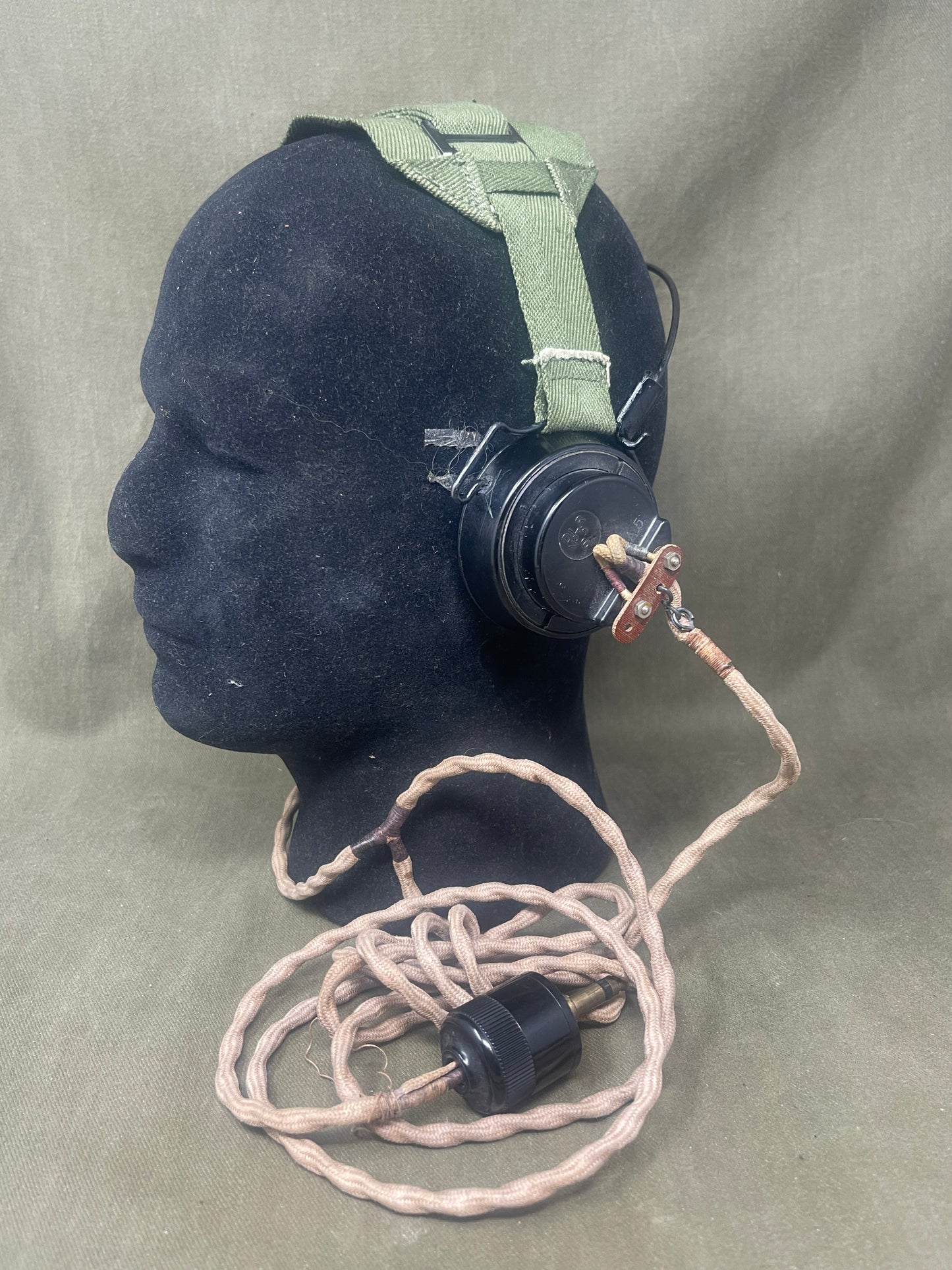 Black airbag with green strap and coiled hose on a gray background