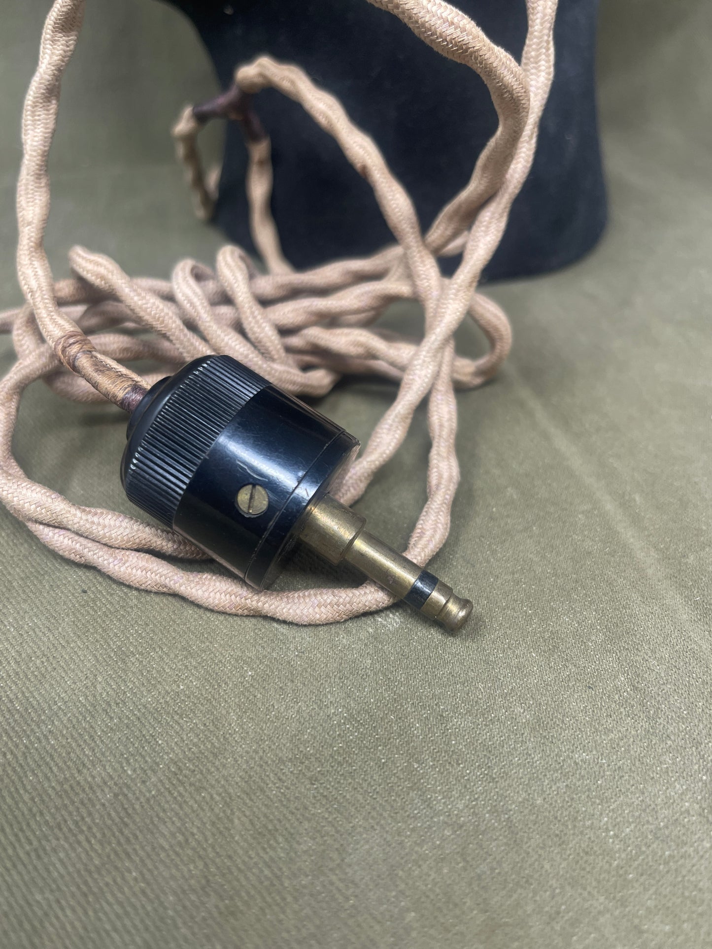 Close-up of a black audio cable connector on a beige cord against a gray background