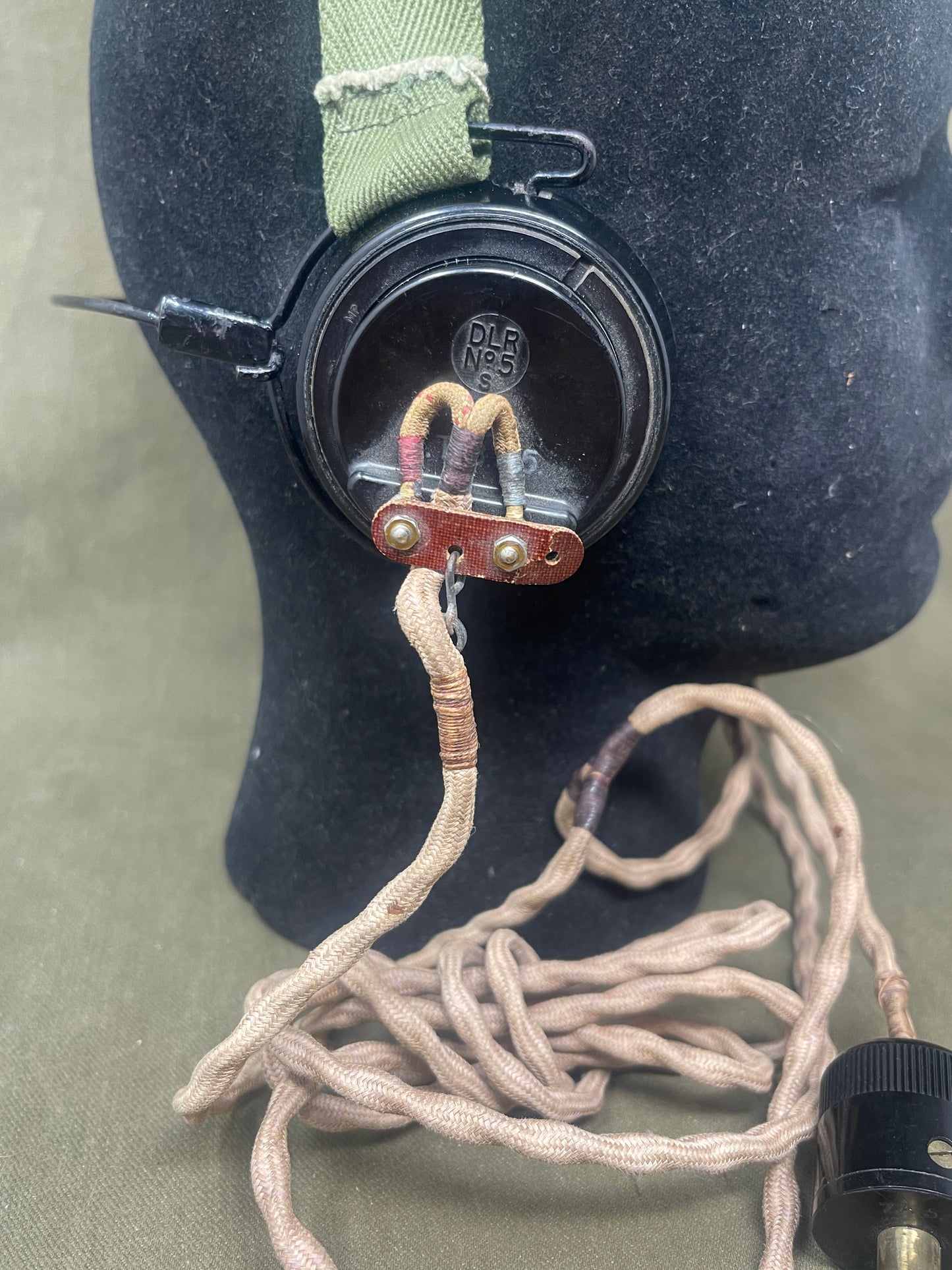 Close-up of a black object with a strap and coiled cable on a green background