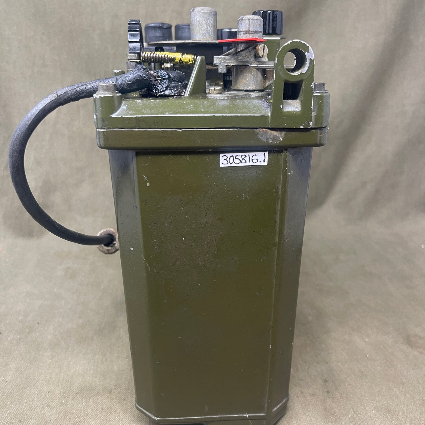 Mechanical device with a rectangular box and cylindrical component on a beige background
