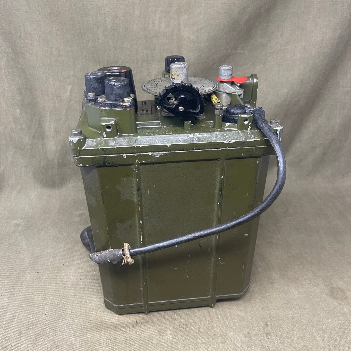 Green metal tank with mechanical components on a gray surface
