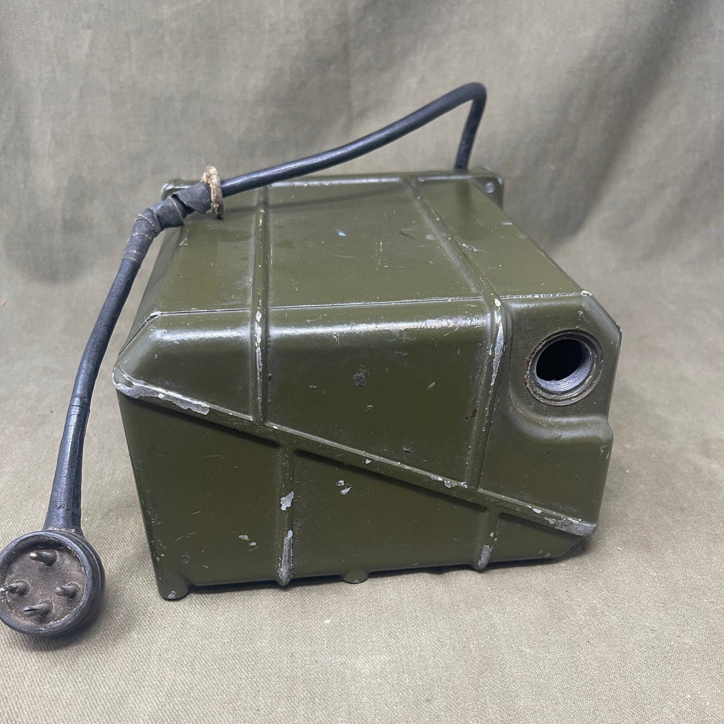 Green metal fuel tank with a hose on a gray surface