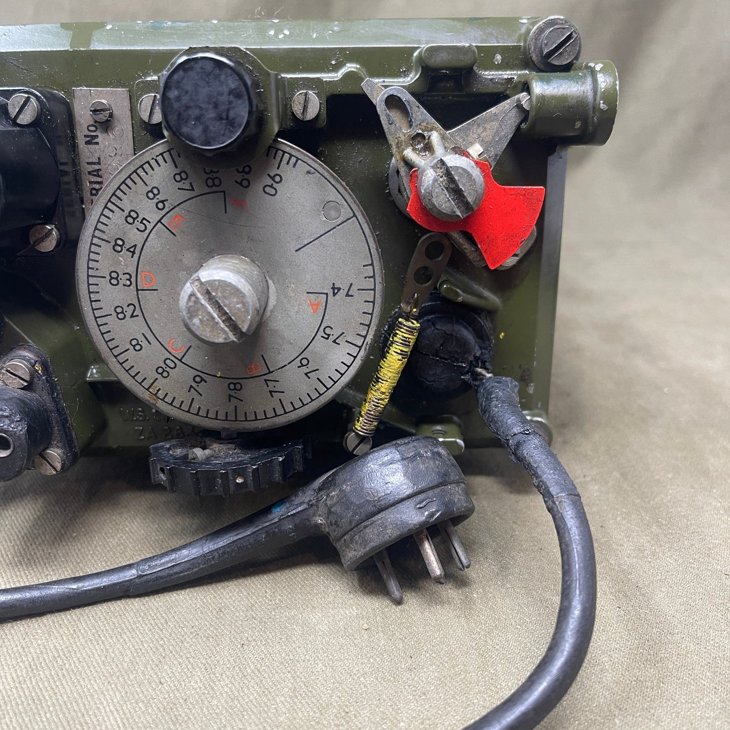 Close-up of an electronic device with dials and wiring on a beige background