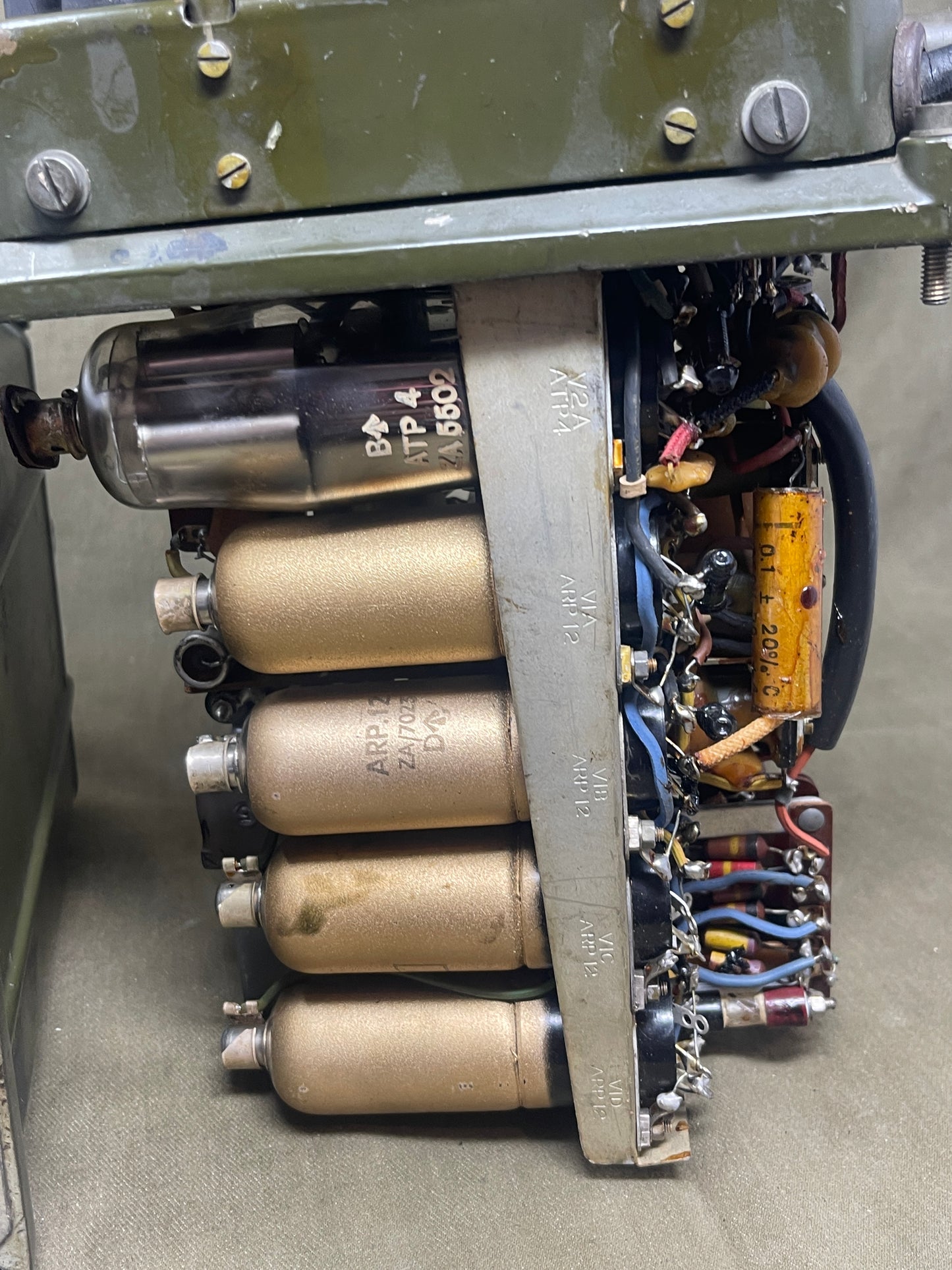 Close-up of an electronic device with vacuum tubes and wiring on a metallic surface.