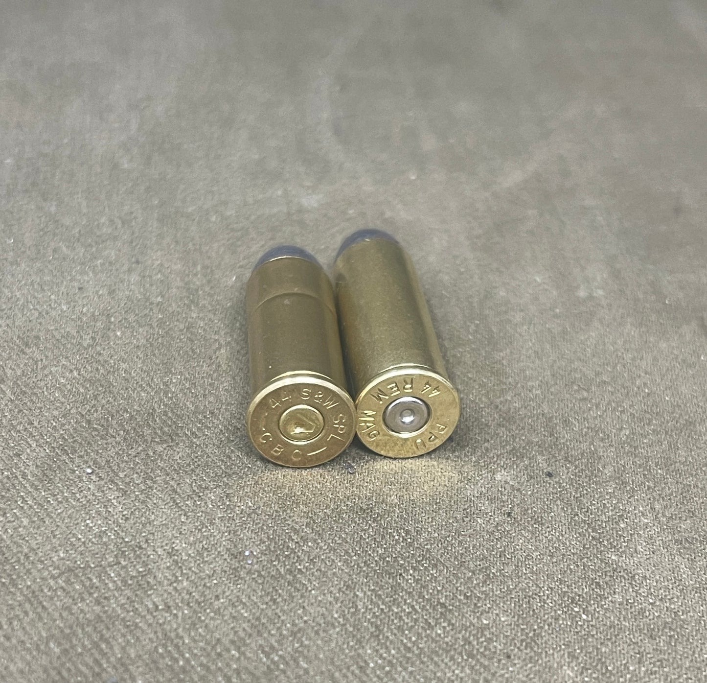 Two brass shotgun shells on a gray textured surface