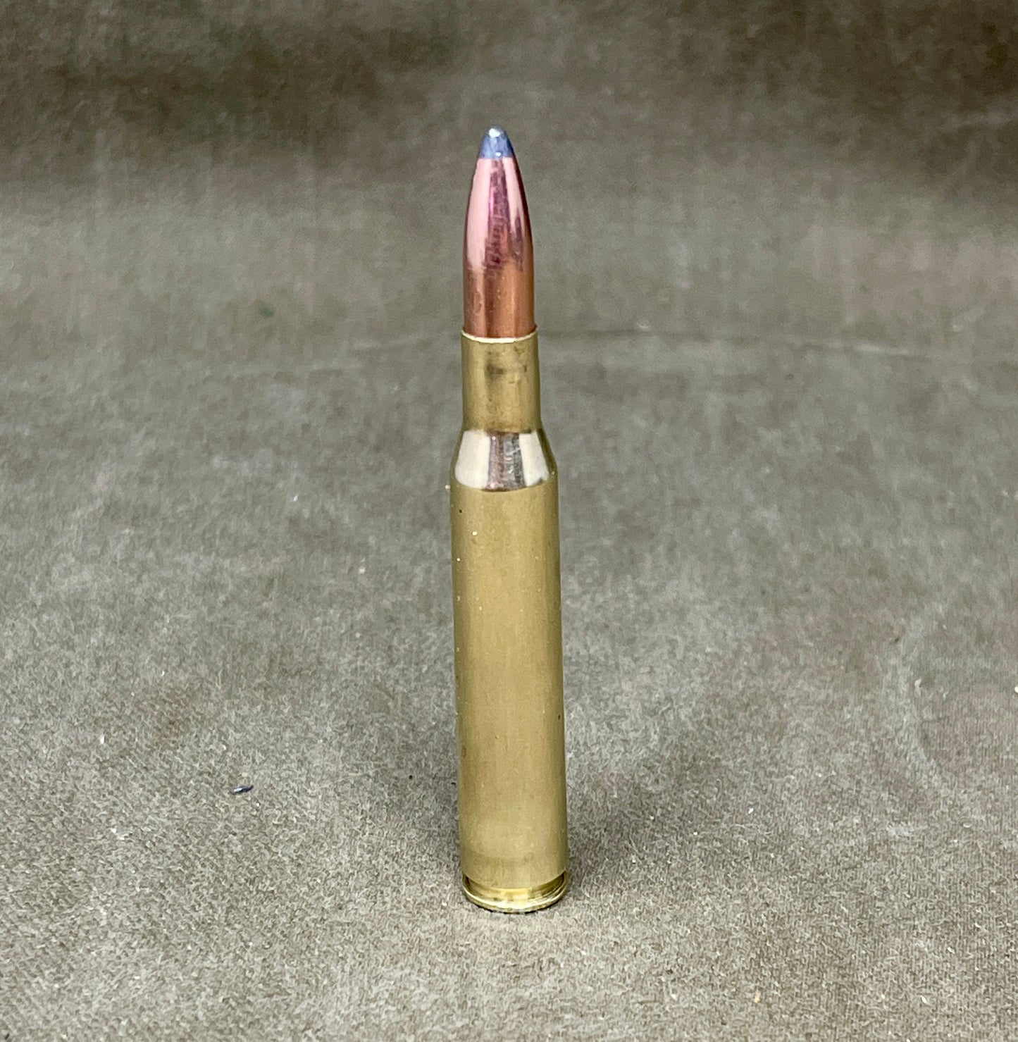 Bullet casing with a blue tip on a gray background