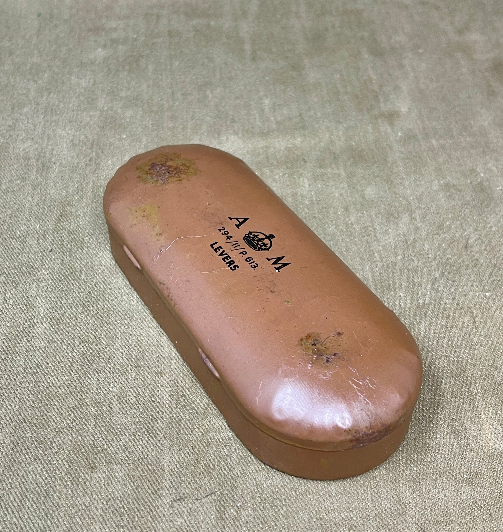 Brown eyeglass case with 'A.M.' branding on a textured surface