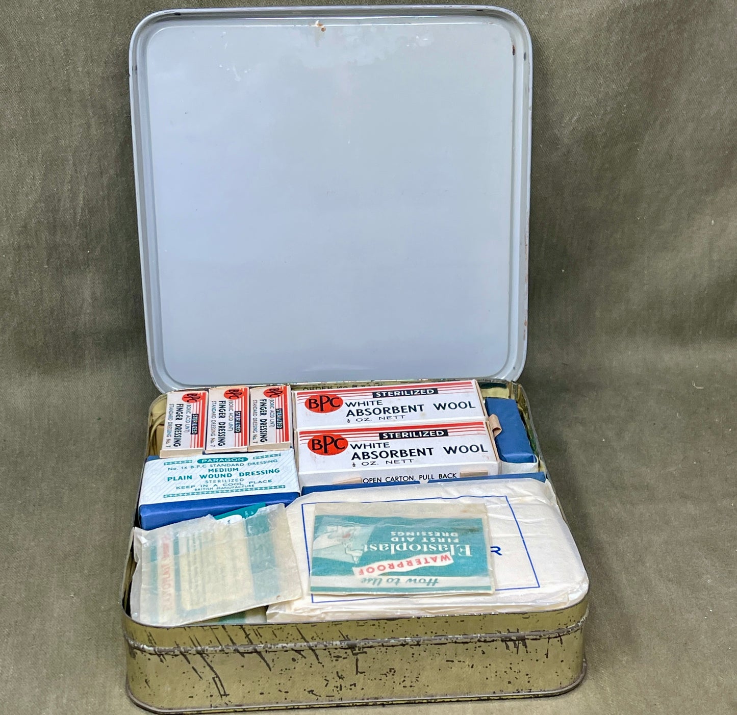 Open first aid kit with various supplies on a gray background