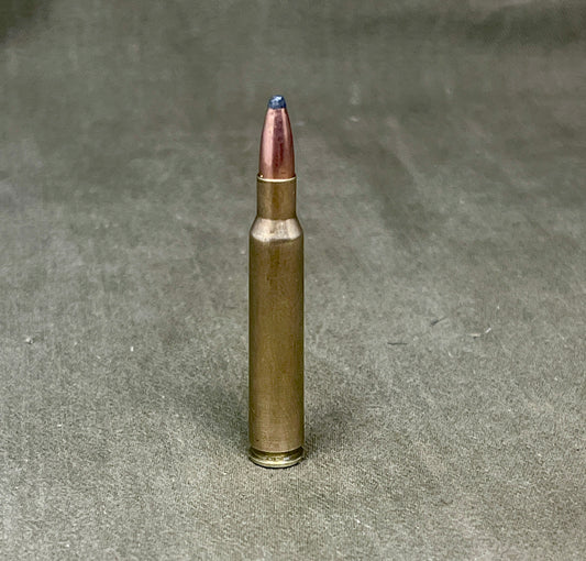 Metallic rifle bullet on a textured gray background