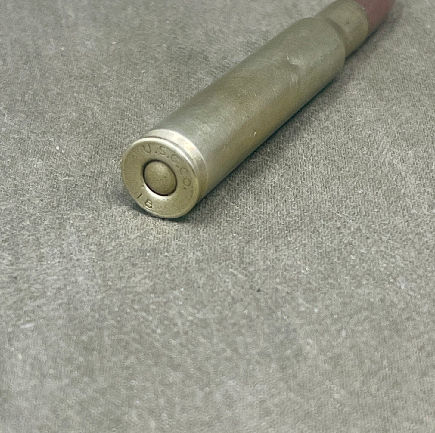 Metallic cylindrical object with 'U.S.' engraving on a gray surface