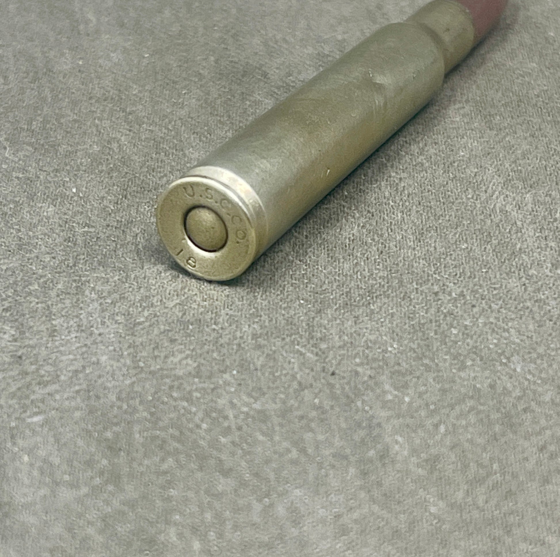 Metallic cylindrical object with 'U.S.' engraving on a gray surface