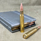 Two rifle cartridges and a magazine on a textured surface