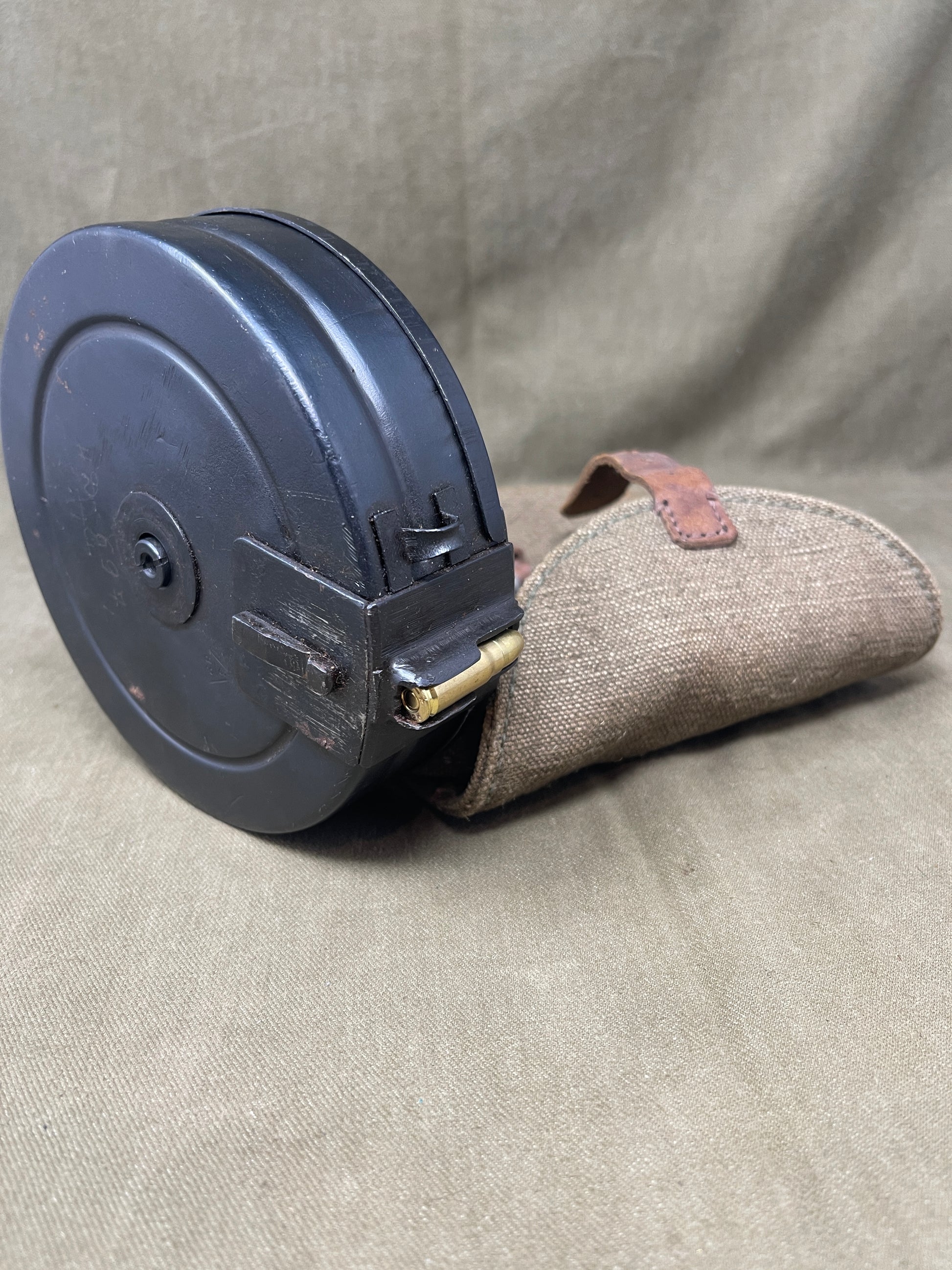 Black ammunition clip with a beige magazine pouch on a beige fabric background