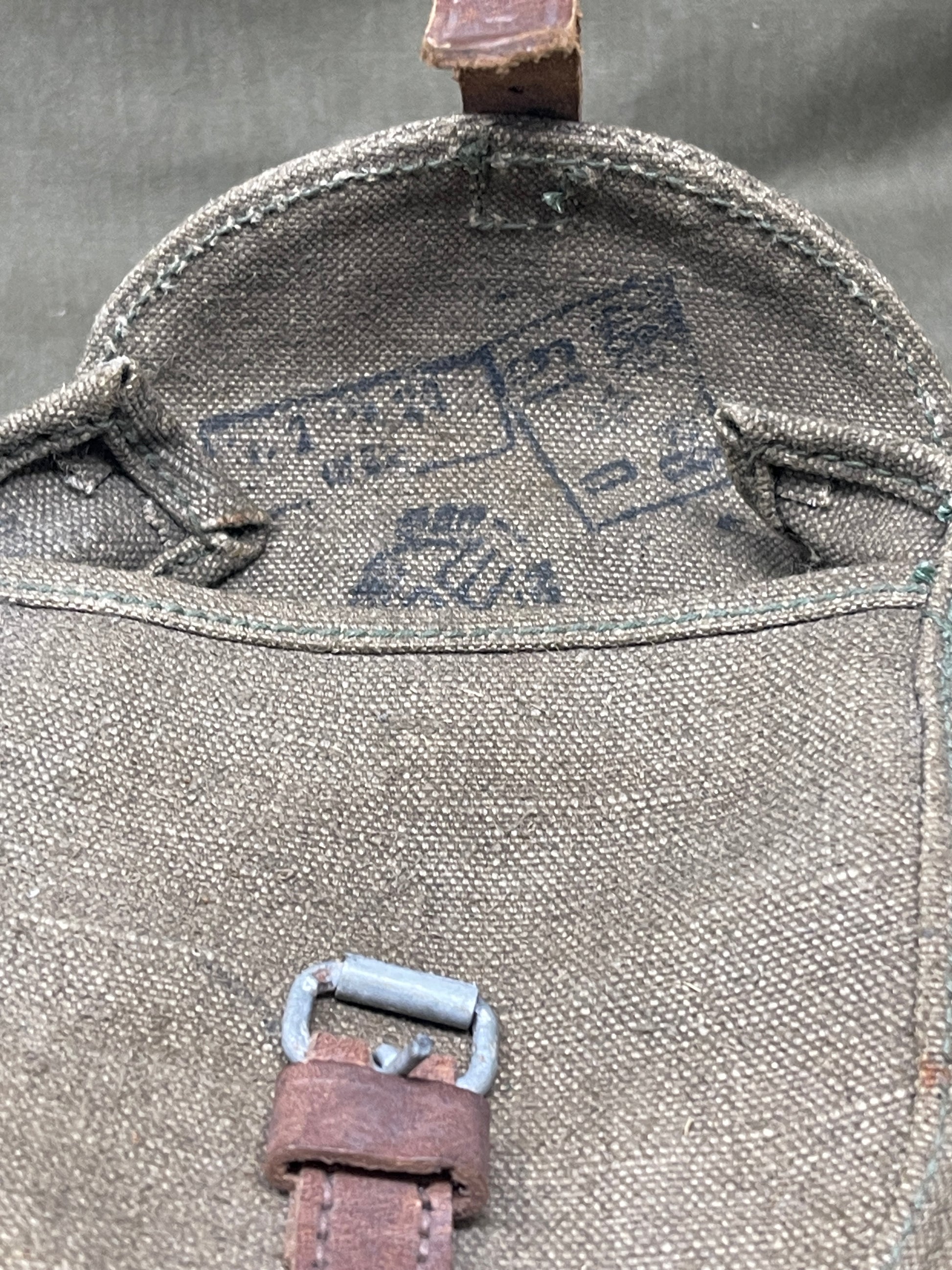 Close-up of a textured fabric bag with leather straps on a gray background