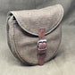 Gray leather bag with a brown strap on a gray background