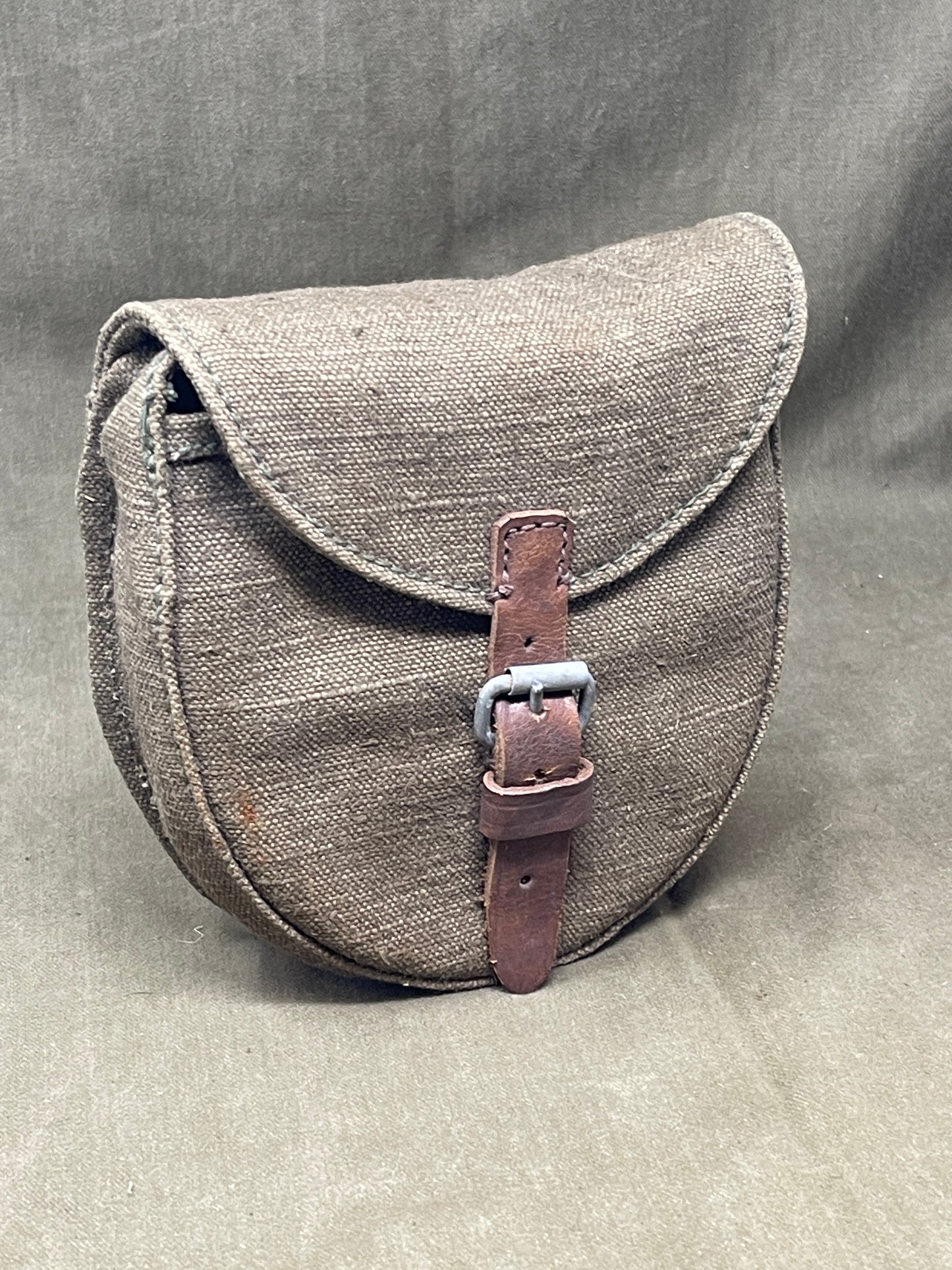 Gray leather bag with a brown strap on a gray background