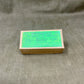 Small cardboard box with green label on a textured gray background