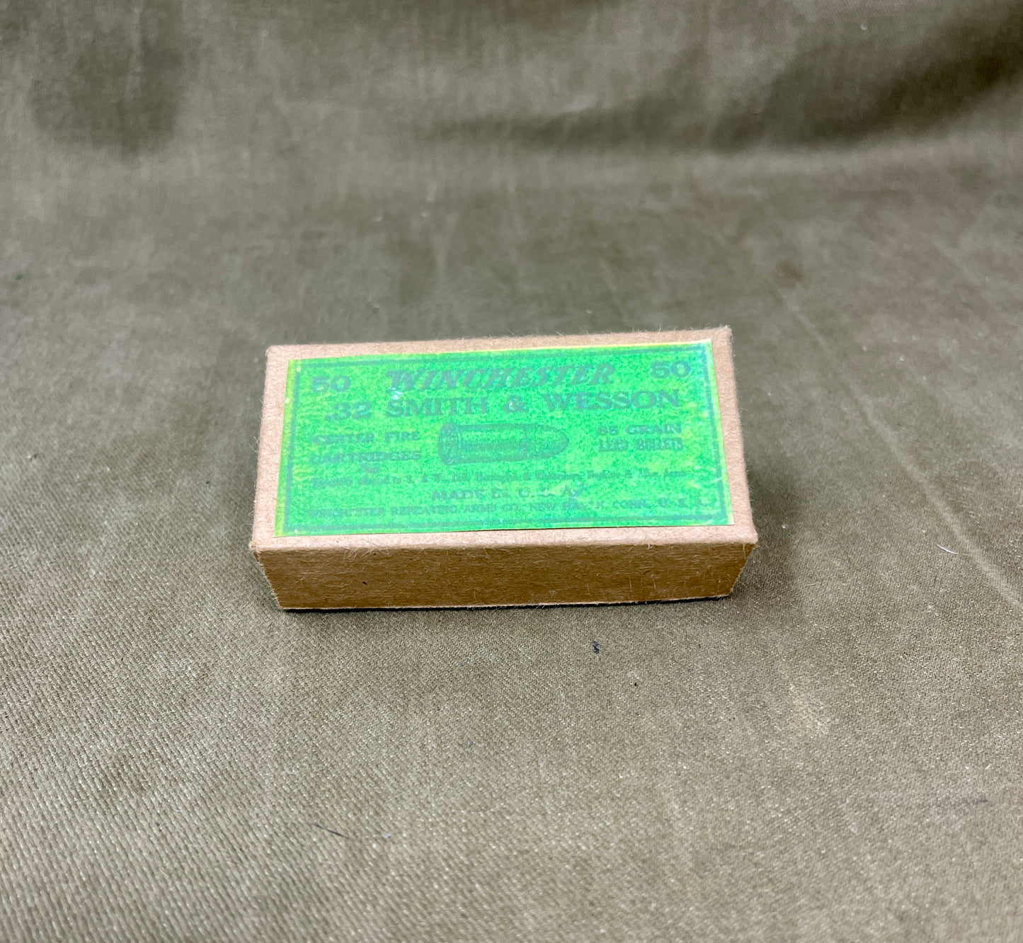 Small cardboard box with green label on a textured gray background