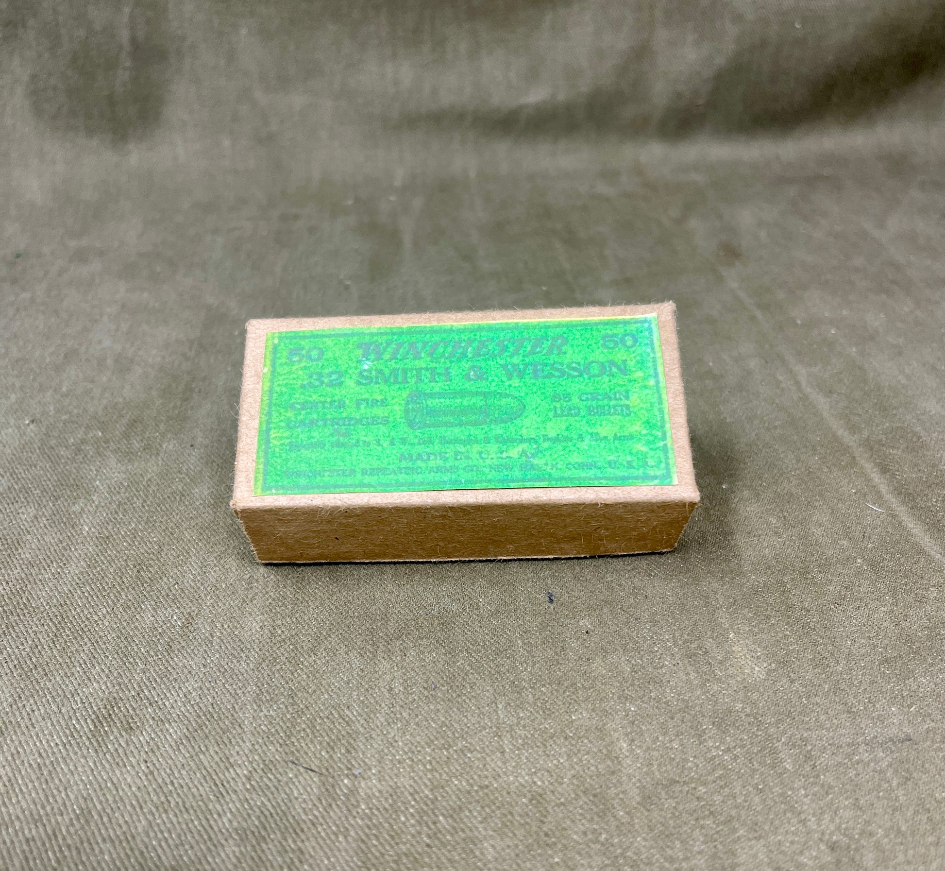 Small cardboard box with green label on a textured gray background