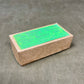 Cardboard box with green label on a gray surface