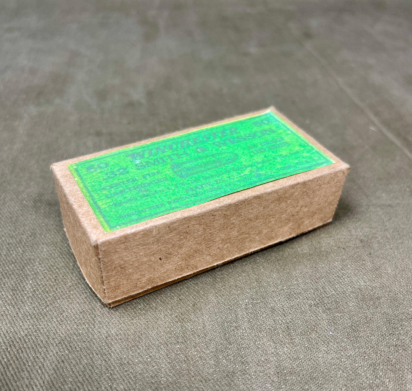 Cardboard box with green label on a gray surface