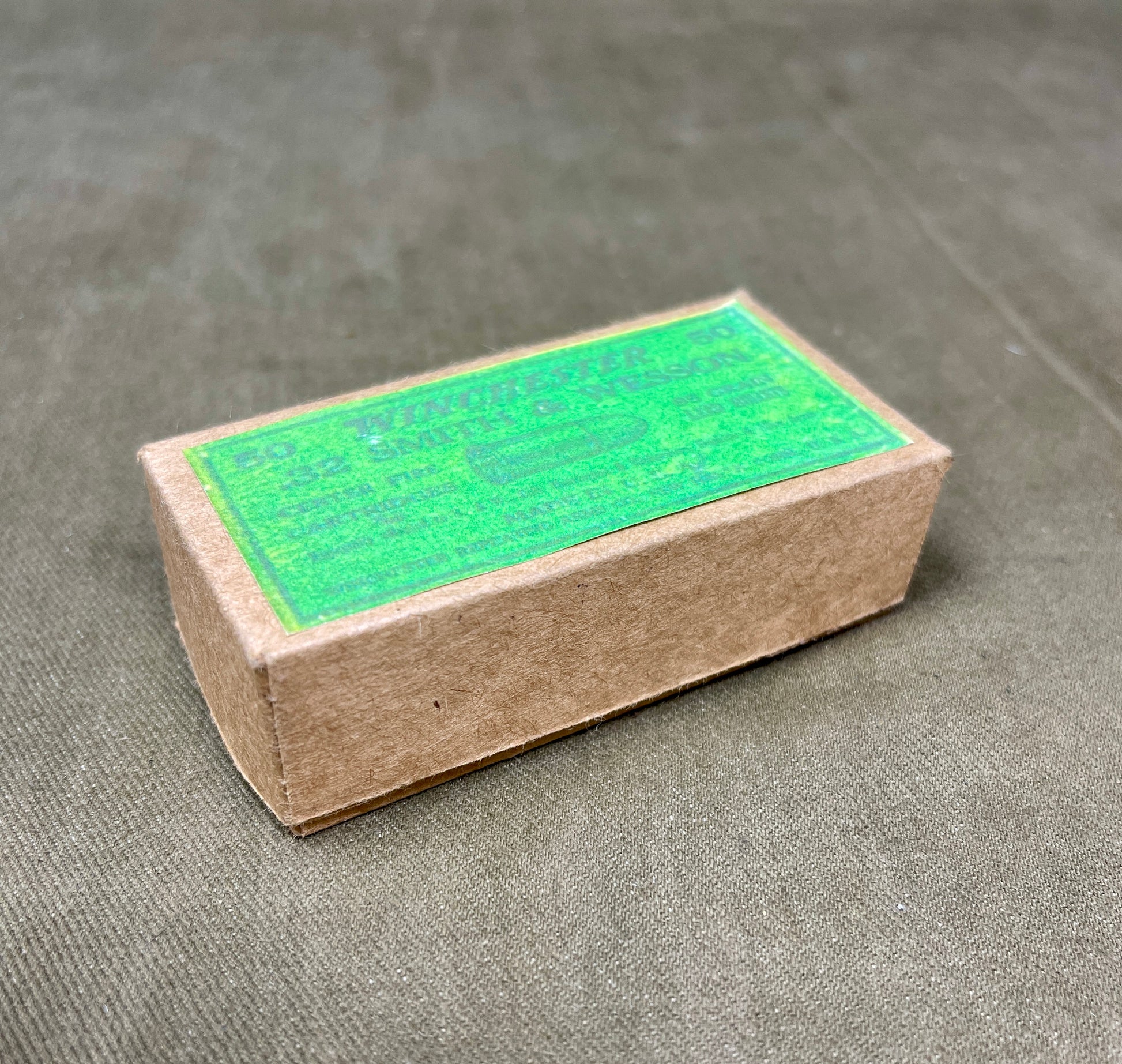 Cardboard box with green label on a gray surface