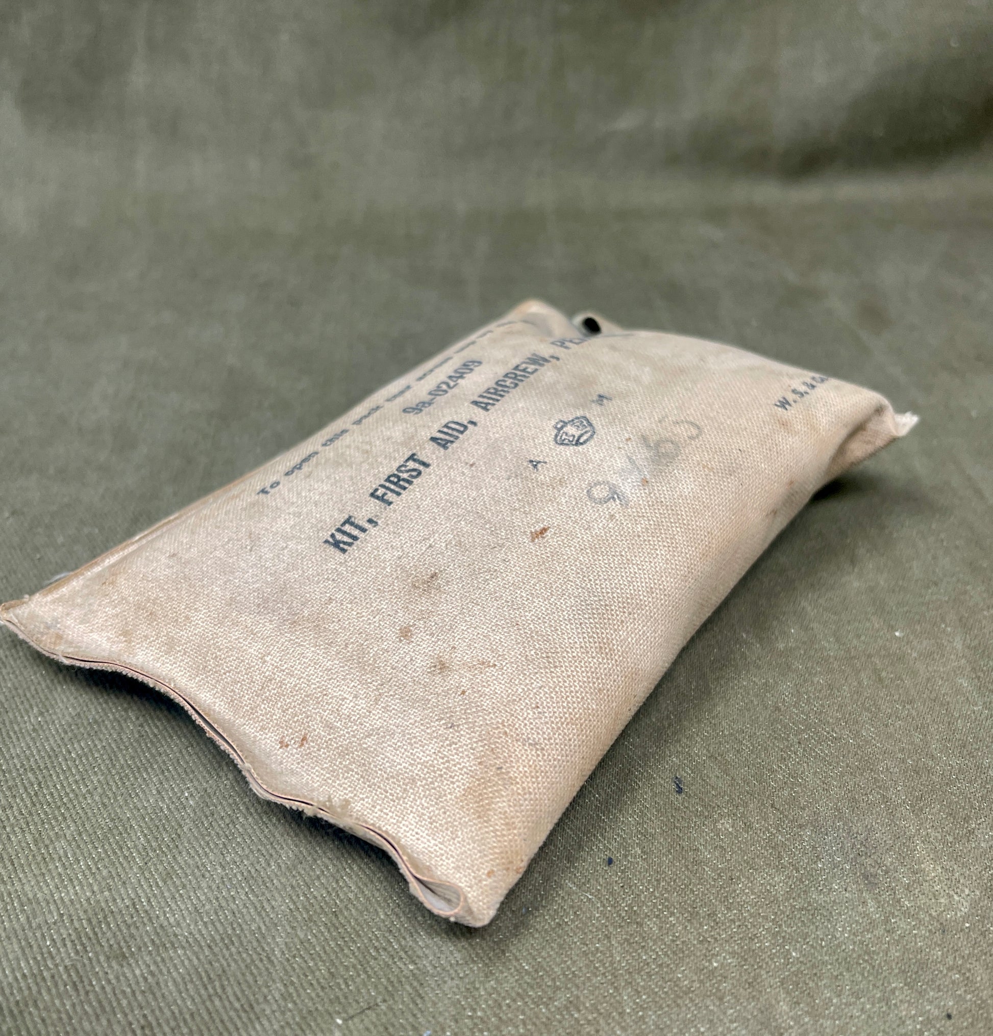 Vintage first aid kit pouch on a textured green background