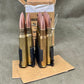 Ammunition cartridges in a holder on a gray surface with cardboard packaging.