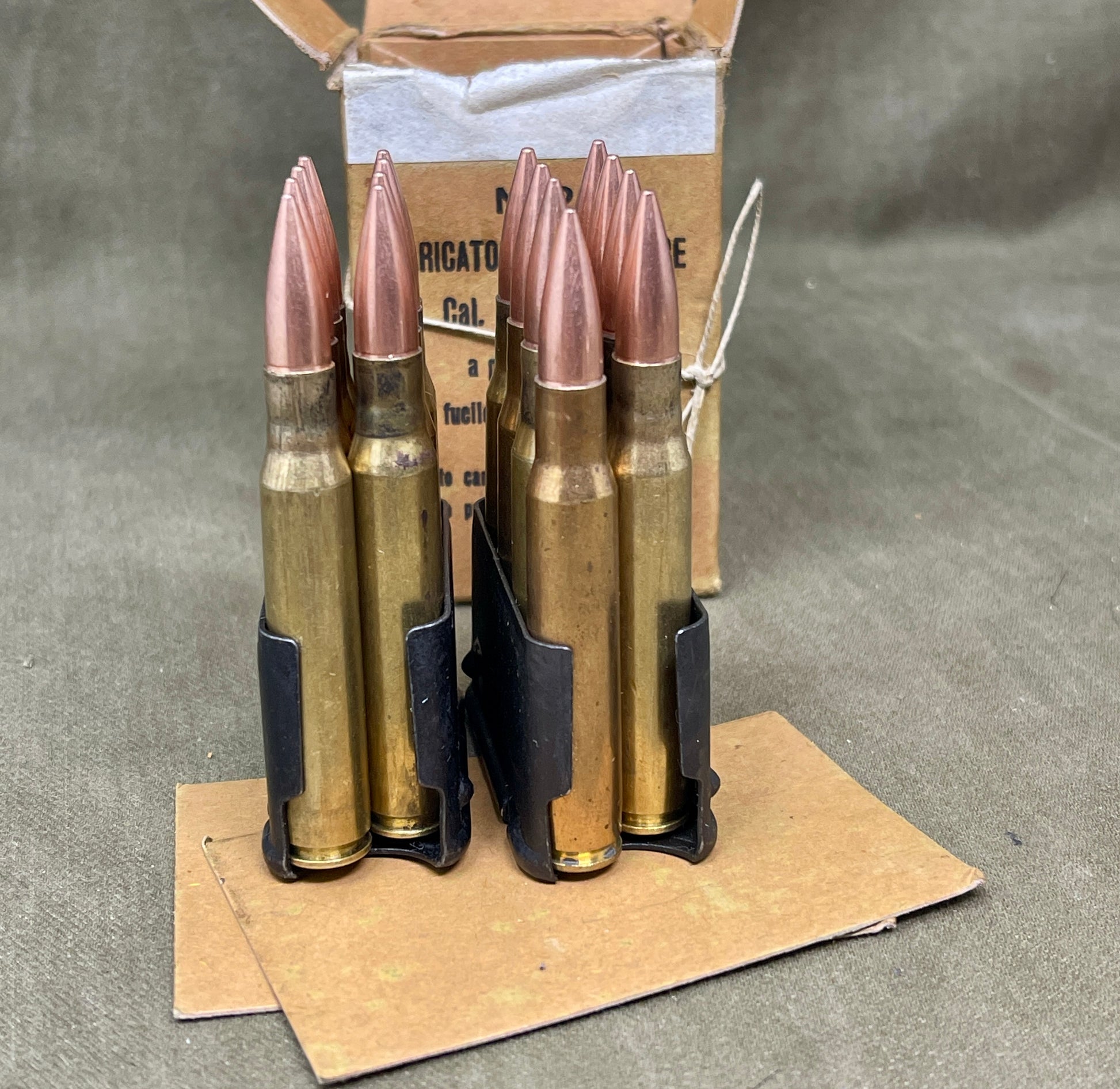 Ammunition cartridges in a holder on a gray surface with cardboard packaging.