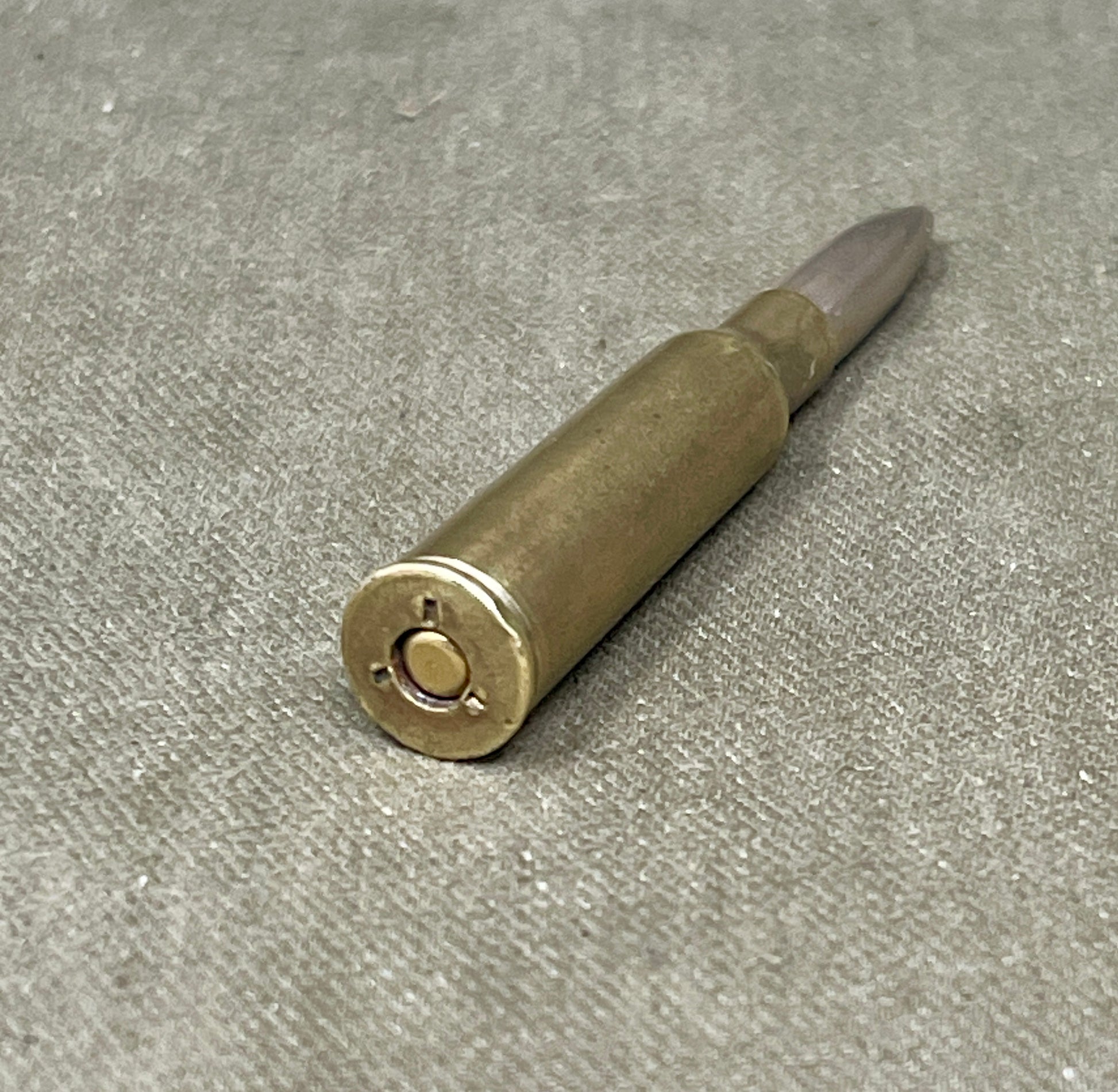 Metallic bullet casing on a gray textured surface