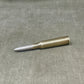 Metallic bullet casing on a gray surface