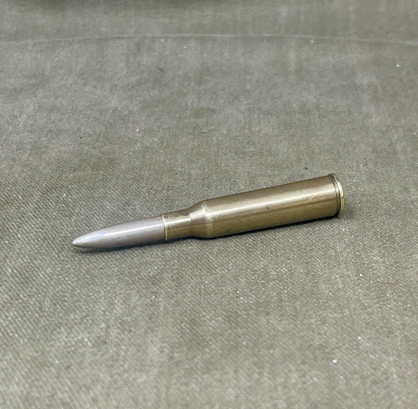 Metallic bullet casing on a gray surface