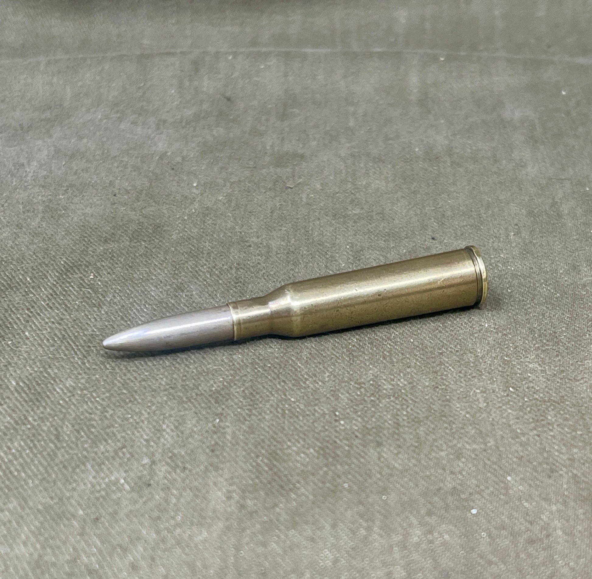 Metallic bullet casing on a gray surface