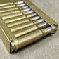 Metallic ammunition casing with bullets on a textured surface