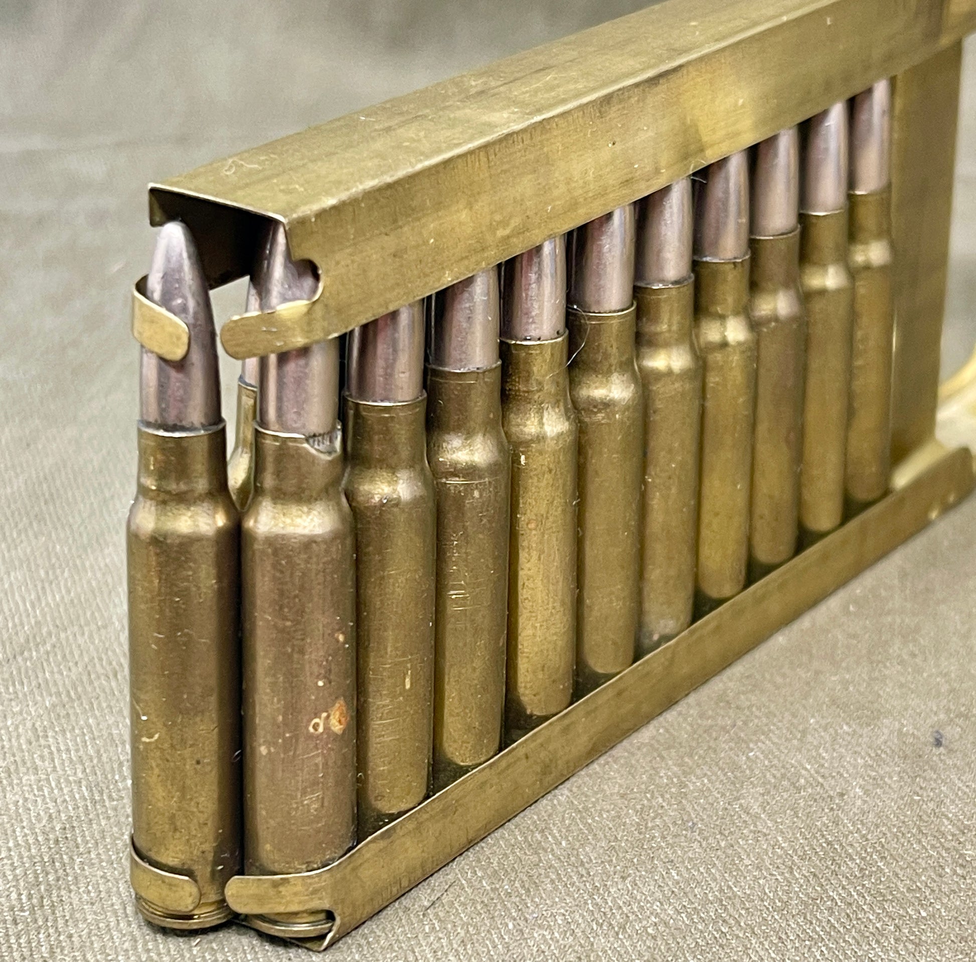 Metallic ammunition cartridges in a brass holder on a textured surface