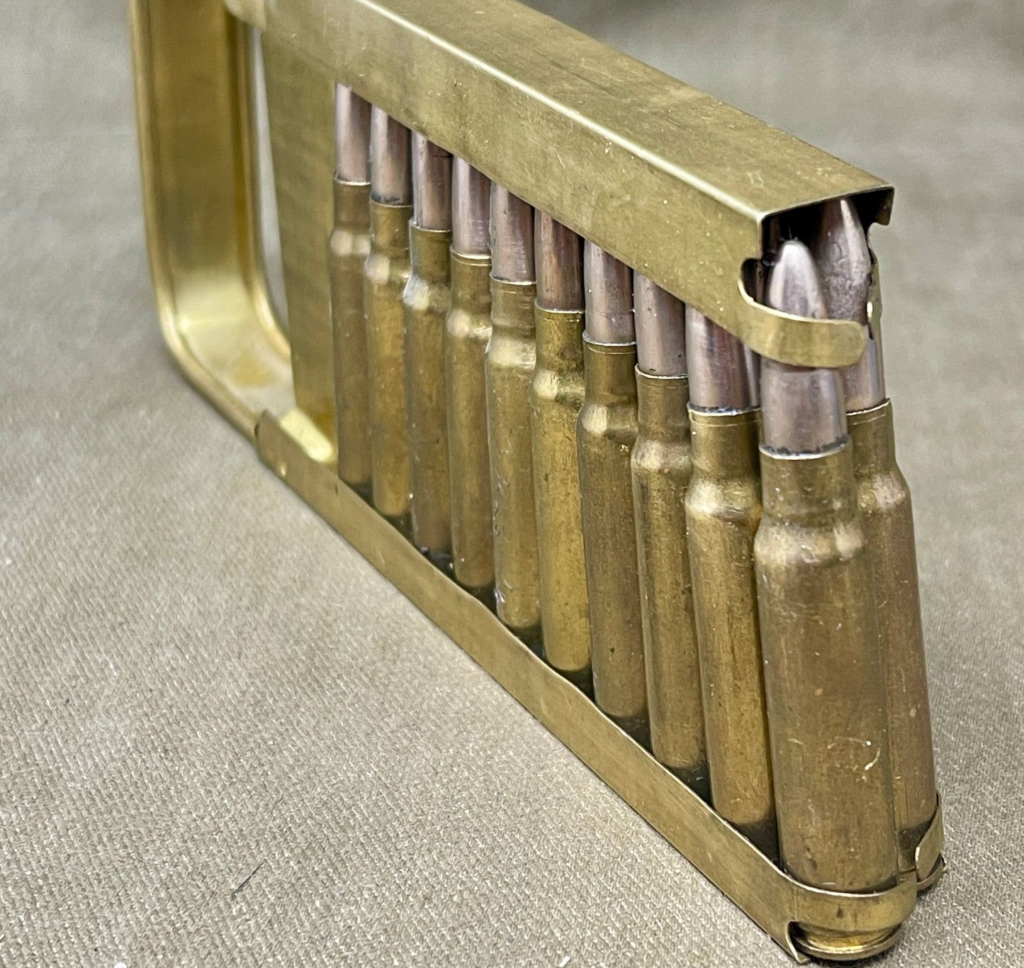 Metallic ammunition clip with bullets on a textured surface