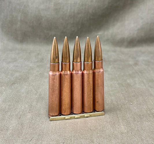 Five rifle cartridges on a textured gray surface